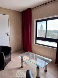 a living room with a glass table and a window at Villa in village in Dāliyat el Karmil