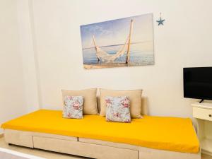 ein Wohnzimmer mit einem gelben Sofa und einem Fernseher in der Unterkunft Gerani Studios in Astypalea-Stadt