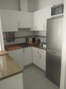 una cucina con armadi bianchi e frigorifero in acciaio inossidabile di Zaharaiso luz a Zahara de los Atunes