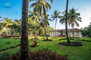 a park with palm trees and a house at Silva Heritage Resort Goa in Benaulim
