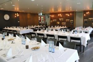 ein Restaurant mit weißen Tischen und Stühlen und einer Uhr in der Unterkunft Richemont Hotel in Luzern