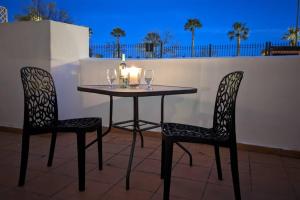 een tafel en twee stoelen met wijnglazen en een kaars bij Spacious and peaceful apartment Jardin 2 in Alhama de Murcia