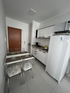 Il comprend une cuisine équipée d'une table et d'un réfrigérateur blanc. dans l'établissement Estúdio Canção Nova Condomínio da Fé, à Cachoeira Paulista