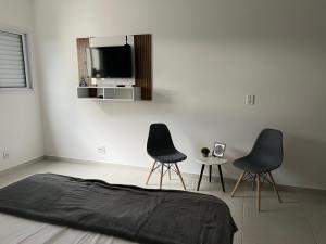 - une chambre avec 2 chaises et une télévision murale dans l'établissement Estúdio Canção Nova Condomínio da Fé, à Cachoeira Paulista