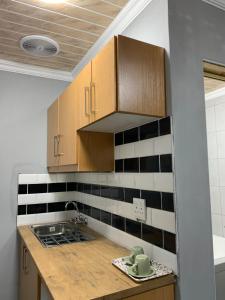 a kitchen with wooden cabinets and black and white tiles at northmead lodge in Benoni