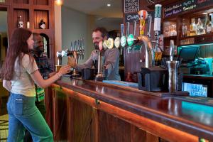 uma mulher parada num bar com um barman em Holiday Inn London Bloomsbury, an IHG Hotel em Londres