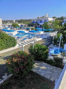 a swimming pool with blue umbrellas in a resort at Flokkas Hotel Apartments in Protaras