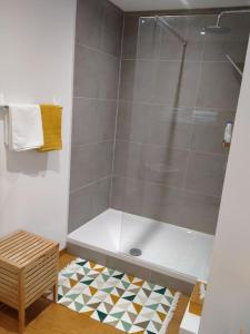 een badkamer met een douche, een bad en een tapijt bij 'Nulle Part Ailleurs' in Dinant