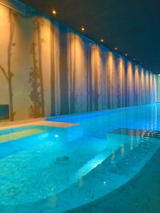 a large swimming pool with blue water and curtains at Natiia Relais - Adults Only in Lazise