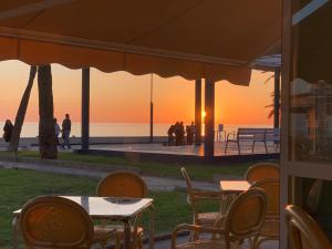 un grupo de mesas y sillas con una puesta de sol en el fondo en Beach Bungalow, en Málaga
