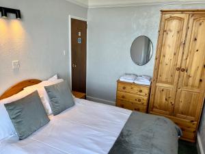 a bedroom with a white bed and a wooden dresser at Capstone View in Ilfracombe