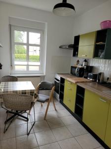cocina con armarios amarillos, mesa y sillas en Carl-Schmäcke-Straße 7, en Neuenhagen
