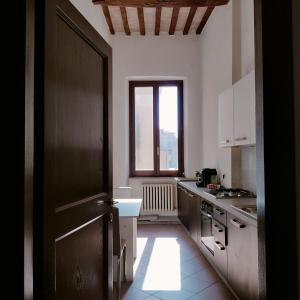 une cuisine avec des placards blancs et une grande fenêtre dans l'établissement St Francis Apartaments, à Foligno