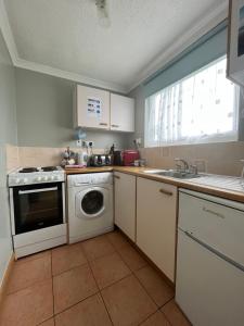 a kitchen with a washing machine and a sink at Bermuda Haven 26, Hemsby - Two bed chalet, sleeps 5, pet free site, onsite entertainment in Great Yarmouth
