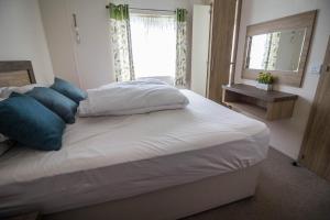 a bedroom with a bed with blue pillows and a window at Luxury Lodge With Full Sea Views At Azure Seas In Suffolk Ref 32105og in Lowestoft