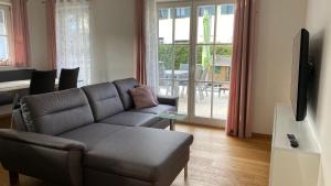 a living room with a leather couch and a television at Lea am See - Bio Design Appartement in Tegernsee