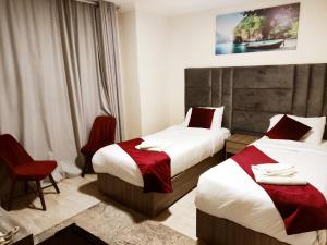two beds in a hotel room with red chairs at Golden Plaza Hotel in Amman