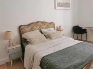 a bedroom with a bed and a table with a chair at Au Petit Faubourg in Grignan
