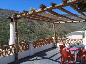 a balcony with red chairs and a table with a view at Casa Los Trillizos in Pampaneira