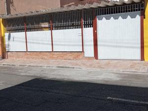 a fence with two white doors on a street at Hostel My House quartos perto do aeroporto de Guarulhos in Guarulhos