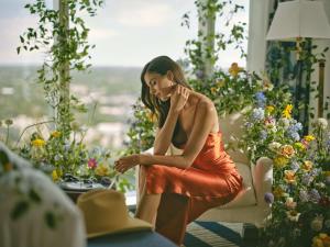 una donna con un vestito arancione seduta in una stanza con dei fiori di Fairmont Austin Gold Experience ad Austin