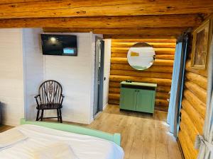 um quarto com uma cama, uma televisão e uma cadeira em Cabana din Groapa Frumoasa em Rasnov