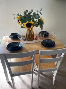 a table with plates and glasses and a vase with flowers at The Hive in South Molton