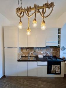 a kitchen with white cabinets and a chandelier at R Home in Ischia Town