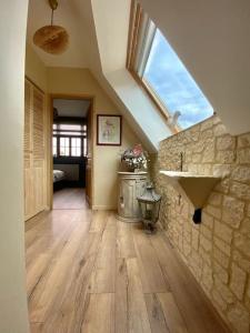 Cette chambre mansardée dispose d'un lavabo et d'un mur en pierre. dans l'établissement Le pigeonnier / Gîte de charme 1 à 4 pers 80 m², à Cambrai