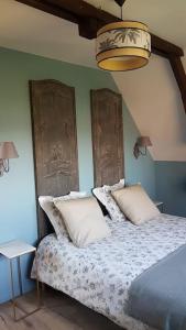 una camera da letto con un letto con cuscini bianchi di Le pigeonnier / Gîte de charme 1 à 4 pers 80 m² a Cambrai