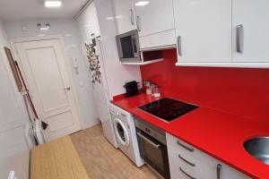 cocina roja con fregadero y fogones en Habitación Privada en el Centro de Madrid, en Madrid