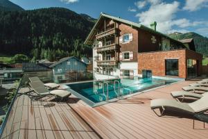 a hotel with a swimming pool and lounge chairs on a deck at Hotel Schwarzer Adler - Sport & Spa in Sankt Anton am Arlberg