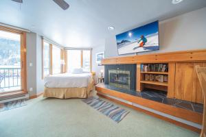 ein Schlafzimmer mit einem Bett und einem TV über einem Kamin in der Unterkunft Lakeside 1476 in Keystone