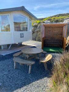 einem Picknicktisch und Bänken vor einem Haus in der Unterkunft Earls View Caravan in Carna