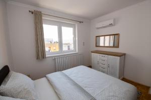 a white bedroom with a bed and a window at Markeeto apartments in Ilijaš