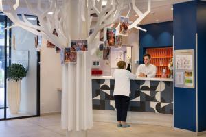 a woman standing at a counter with a man behind it at Domitys - Galilée in Cergy