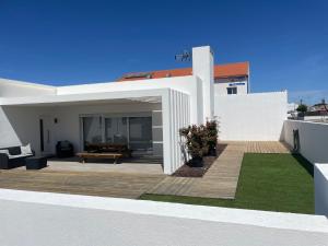 ein weißes Haus mit Terrasse und Rasen in der Unterkunft Casa Sofia in Carvalhal