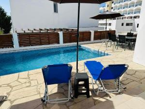 duas cadeiras azuis e um guarda-sol ao lado de uma piscina em Villa Mulberry Retreat 0,5Km From Everything em Coral Bay