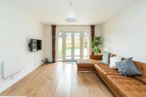 a living room with a couch and a television at Sleek and Stylish 2BD Home with a Garden Anerley in London