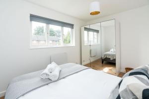 - une chambre blanche avec un lit et un miroir dans l'établissement Sleek and Stylish 2BD Home with a Garden Anerley, à Londres