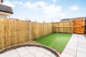 a backyard with a wooden fence and a green lawn at Sleek and Stylish 2BD Home with a Garden Anerley in London