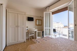 a bedroom with a bed and a desk and a balcony at Hotel Aida in Alassio