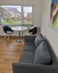 a living room with a couch and a table and two chairs at Moderne Ferienwohnung Gartenblick in Amtzell
