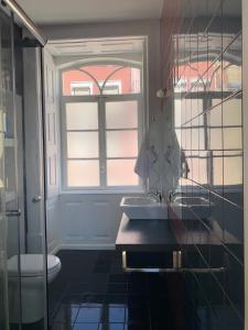 baño con lavabo, ventana y aseo en Rua visconde de luz 100, en Coímbra