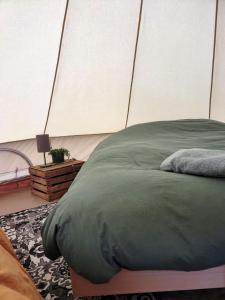 a bedroom with a large green bed with a wall at Pluimpapaver Hotel & Glamping in Aarschot
