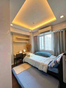een slaapkamer met een groot bed en een raam bij Modern 2-bedroom suite for 5 across MOA in Manilla