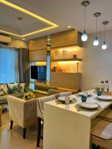 een keuken en een woonkamer met een tafel en een bank bij Modern 2-bedroom suite for 5 across MOA in Manilla