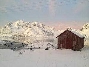 a painting of a red barn in front of snow covered mountains at FLO Lofoten nature escape in Valberg +12 photos