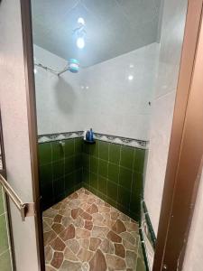 y baño con ducha de azulejos verdes y techo. en CasaBlanca Avcircunvalar, en Duitama