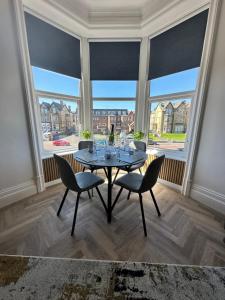 a dining room with a table and chairs and large windows at No 3 ,luxury 2 bed 1st floor apartment with free parking,Lytham St Annes in Saint Annes on the Sea
